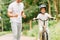 View of father cheering son while boy riding bicycle and looking at camera