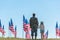 View of father in military uniform holding hands with child near american flags