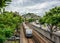View of favela, grey sky, green trees, railroad tracks and subway train arriving to Inhauma station