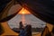 View of female legs in a tourist tent at sunset on the beach. The woman is hiking and camped on the riverbank.