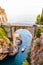 View on Fiordo di Furore arc bridge built between high rocky cliffs above the Tyrrhenian sea bay in Campania region. Cars driving