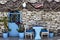 View of fish nets, blue chairs, door, pots and stone wall