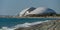 View of Fisht stadium from Olympic Embankment in Sirius. Blue waves and gray pebbles of Black Sea coast.