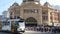 View of Flinders Street Station with people walking and tram crossing street