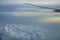 View of fluffy abstract white cloud and blue sky with airplane wing and sunrise light background from airplane window
