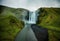 View from flying drone. Dramatic midnight sun scene of Skogafoss Waterfall