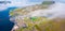 View from flying drone. Foggy morning cityscape of Eidi town. Aerial summer view of Eysturoy island. Bright seascape of Atlantic o