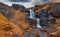 View from flying drone. Incredible evening view of nameless waterfall on Rauda river. Yellow hills on the southern coast of Icelan