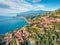 View from flying drone. Sunny morning view of Taormina town and Etna volcano on background. Nice spring seascape of Mediterranean