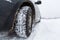 View focused on the car tire and  bumper  on winter road covered with snow. Vehicle on snowy road after snowfall.