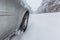 View focused on the car tire during in motion on snowy rural road during snowfall.