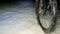 The view follows the front wheel of the mtb bouncing over the frozen snow of the path. Dangerous ride on a slippery ground