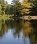 View of forest and reflections from the kayak on the lake in autumn