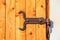 View of the forged medieval door hinge on the wooden plank gate close-up