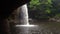 View form Cave under the Picturesque Waterfall in Jungles at Evening Time. Water is Falls in Pool through Sun Beams at