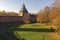 View of the fortress wall of the Novgorod Kremlin surrounded by autumn colors of trees.