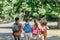 View of four multicultural friends with backpacks running in summer park