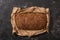 View of fresh baked loaf of whole grain bread in paper on stone black surface