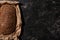 View of fresh baked loaf of whole grain bread in paper on stone black surface