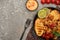 View of fried shrimps with sauce, fork, grilled toasts, vegetables and lime on grey concrete background