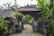 View of the front door in a stone fence surrounded by green plants. Housing villa in the tropics. Bali, Indonesia