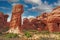 View on funny eroded red rugged sandstone formation with stone pillar and natural arch in dry environment against blue sky with