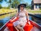 View of girl with blond hair and blue hat sit on a boat ride at the river in famous typical Dutch village Giethoorn