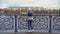 View of girls from back standing on pier. Young woman in warm clothes standing at steel railing of pier. Views of autumn