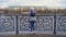 View of girls from back standing on pier. Young woman in warm clothes standing at steel railing of pier. Views of autumn