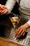 view of glass with drink in which bartender adds drop of ingredient