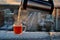 View of a glass mug with hot tea poured into it from a thermos on the snow-covered parapet of the roof