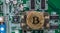 View of a golden bitcoin placed on a chipset of a graphics card with lots of circuitry and processors