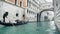 View of gondola with tourists under the Bridge of Sighs in Venice, rainy day