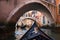 View from gondola under old bridge in street of Venice