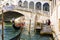 View of gondolas on Grand canal and Ponte di Rialto, many tourists on a bridge