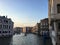 A view of the grand canal in Venice, Italy during sundown.  There are only a few small boats going down the canal as the sun sets