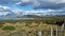 View of granite snow-capped peaks behind scrub field and sapphire blue lake in Patagonia, Chile