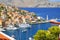 View on Greek sea Symi island harbor port, classical ship yachts, houses on island hills, tourists Aegean Sea bay. Greece islandsV