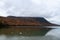 View of a green autumn mountain reflecting on the Lake Willoughby, South Beach, buoys, clouds