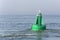 View on a green buoy in the sea, a device to safeguard ships and boats.