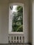 View of the green garden through the white arch of the house. Tranquility scene of nature. Vertical photo.
