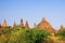 View green grass and bush on group of towers of ancient buddhist brick stone stupas spread across the plain of Bagan