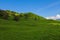 View of the green hills and mountainsides. A clear sunny day. On the slopes in the distance sheep and cows graze. Selective focus