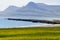 The view of green landscape, rock formations and cliffs by the ocean near East Fjords, Iceland during the summer