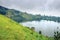 View of green mountains with a Crater Lake and the reflections on the water on a cloudy overcast day, Rweteera, Fort Portal