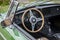 View into an green oldtimer convertible car with a wooden steer