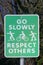 A View of green road sign `Go slowly, respect others`