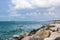 A view of the green sea, blue sky, cloudy sky, and rocks at the right corner of the picture