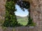 View of a green valley through the window of a ruin