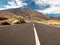 View from the ground on long highway and painted lane lines going through desert and mountains